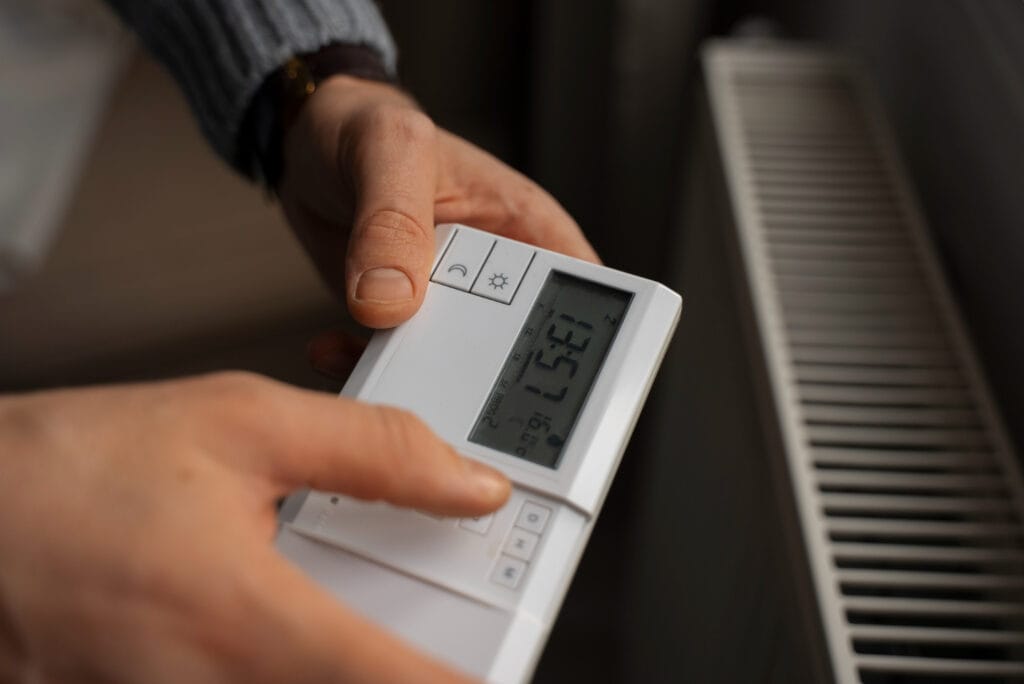 homme qui règle un thermostat